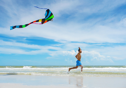 Young man flying a kite on an empty Florida beach
