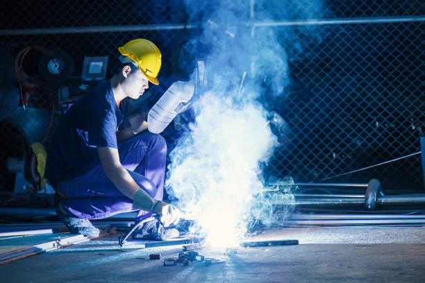 Worker while doing a welding with arc welder with the smoke, man wearing mask with his hands welding in heavy industry Worker while doing a welding with arc welder with the smoke, man wearing mask with his hands welding in heavy industry oxyacetylene stock pictures, royalty-free photos & images