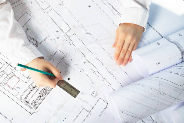 istock architect designer working on architectural blueprints, building plans in the office, drawing 1262836439
