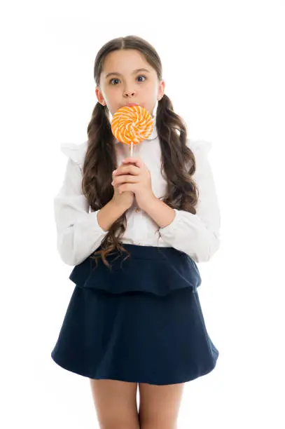Sweets reward for study. Rewarding herself with sweets. Food addictions. Girl kid eat sweet lollipop. Girl pupil school uniform like sweets lollipop candy white background. Healthy nutrition diet.