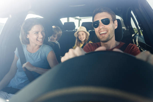 Happy family enjoying in their trip by car. Happy parents and their kids enjoying while traveling by car. The view is through windshield. family in car stock pictures, royalty-free photos & images