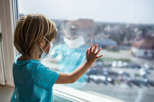 istock Sad little boy looking through window during quarantine at home. 1262849167