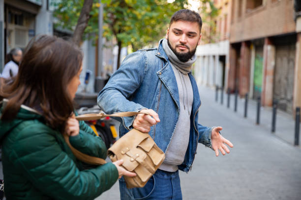 guy snatching handbag of woman on street - woman reaching into handbag imagens e fotografias de stock