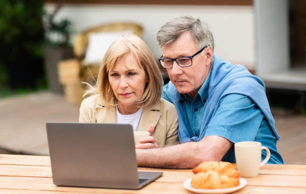 istock Serious mature couple using laptop computer near camper van outside 1262860900