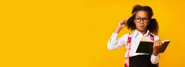 istock Schoolgirl Thinking Holding Book Doing Homework Over Yellow Background, Panorama 1262861439