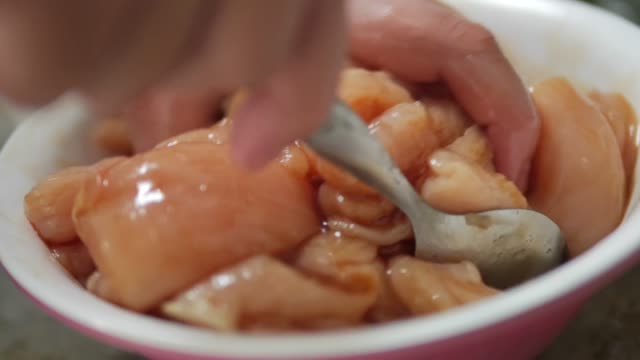 Boy hand applying pepper sugar and soy souce for marinated chicken in bowl, slow motion.