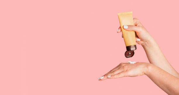 milenium kobieta stosując krem do rąk z rurki na różowym tle, puste miejsce - moisturizer cosmetics merchandise human hand zdjęcia i obrazy z banku zdjęć