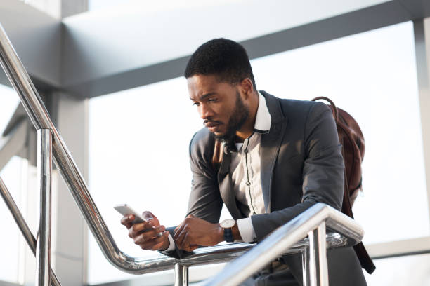 istock Black Business Guy Using Cellphone Standing At Rail Station 1262872883
