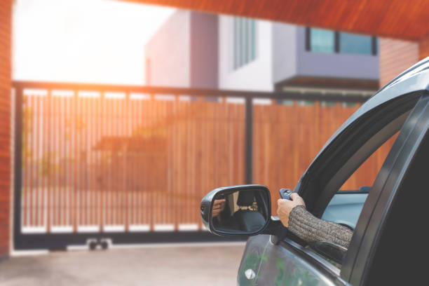 Remote control Woman in car, hand holding and using remote control to open the auto gate when driving and arrive home. Security system and save time concept. thai door stock pictures, royalty-free photos & images