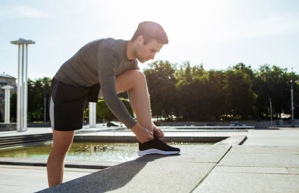 istock Start of marathon. Young handsome man tying shoelaces on steps 1262877551