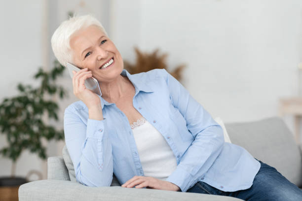 istock Mobile Communication Concept. Cheerful Elderly Lady Talking On Cellphone At Home 1262878827