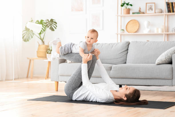 young mother training together with baby at home, balancing son on legs - mother exercising baby dieting imagens e fotografias de stock