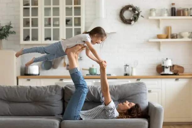 Photo of Overjoyed small kid girl practicing acroyoga with mom.