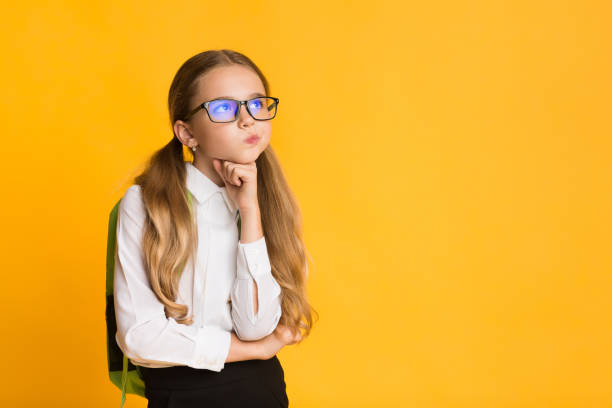 istock Thoughtful Elementary Schoolgirl Thinking Standing Over Yellow Background 1262888453