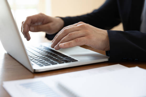 istock Businessman sitting at desk typing on laptop close up image 1262889143