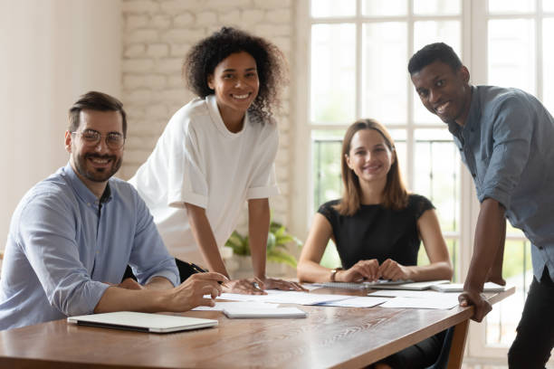 istock Five multiethnic businesspeople gather in boardroom smiling posing for camera 1262889221