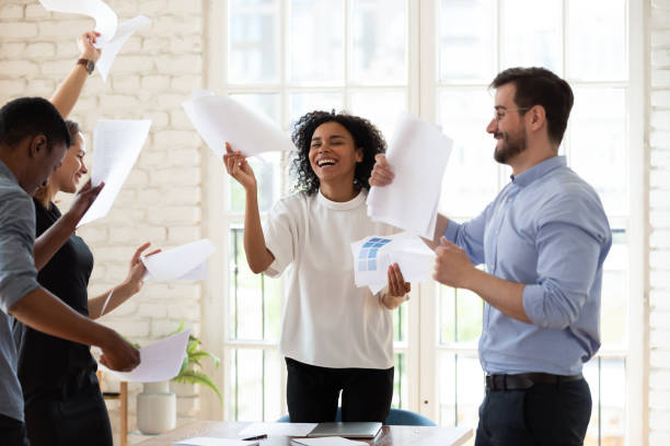 istock Multiracial staff members dancing throwing papers feels overjoyed ending workday 1262889243