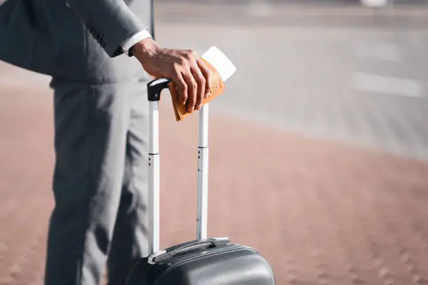 Business Trip. Unrecognizable Businessman Holding Passport And Boarding Pass Standing With Travel Suitcase Outdoor At Airport. Closeup, Cropped, Copy Space