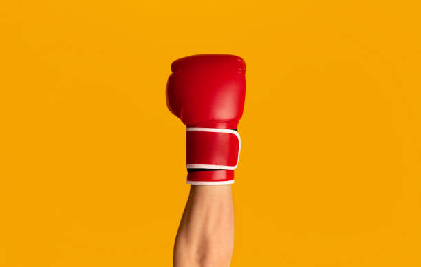 deportista usando guante de boxeo sobre fondo naranja, primer plano de la mano - guante deportivo fotografías e imágenes de stock