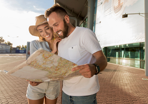 Happy spouses waiting to board a plane and looking at the map of the tourist destinations they want to visit, outdoors