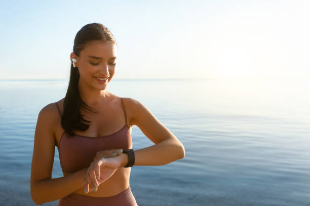 istock Happy healthy girl running on the beach, using tracker 1262893235