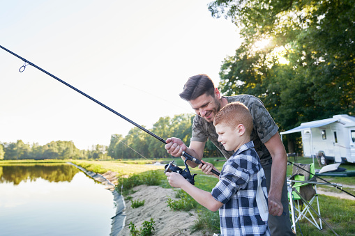 Father Teaching Son To Fish By Lake