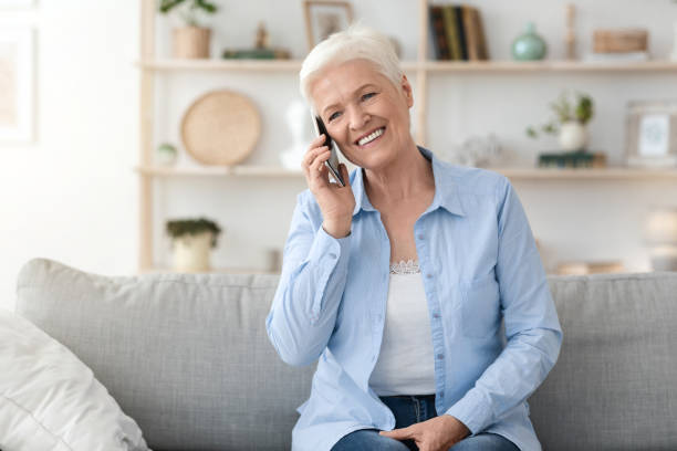 istock Communication Concept. Smiling elderly woman talking on mobile phone at home 1262894992