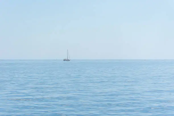 Photo of A lone sailboat against the blue sea and sky