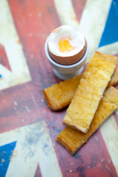Breakfast with boiled eggs, bread, and butter on a white table.