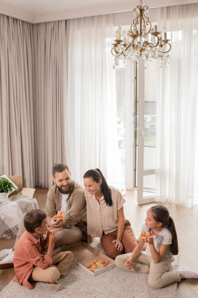 istock Happy family eating pizza on floor 1262902148