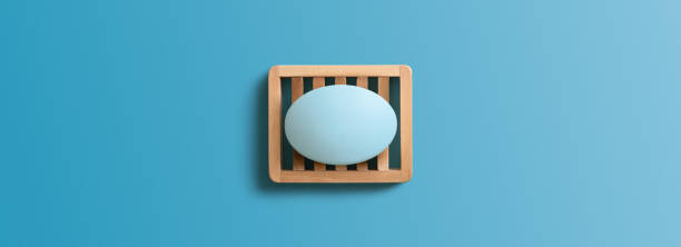 barra de jabón en plato de madera sobre fondo azul. directamente arriba, copia el espacio. - jabonera fotografías e imágenes de stock