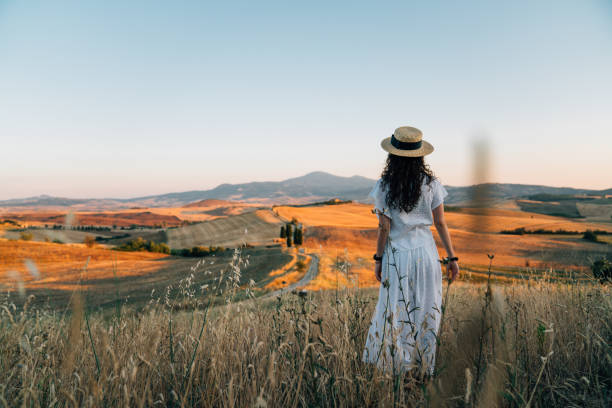 młoda kobieta podziwia zachód słońca na polu pszenicy w toskanii - tuscany landscape italy siena zdjęcia i obrazy z banku zdjęć