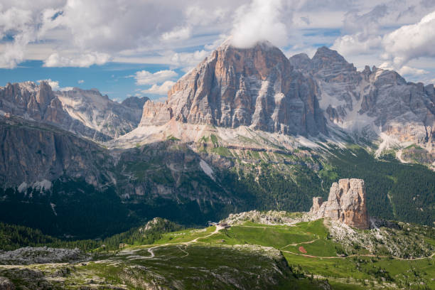 Vast mountain landscape with green meadows, forested valley and steep peaks. The photo was taken in sunny, summer day during Alta Via trek in Italian Dolomites. stock photo
