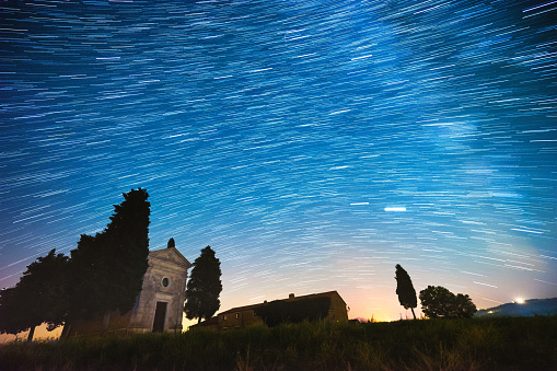 Night star trails over Vitaleta Chapel in Val d'Orcia, Siena Province, Tuscany. Madonna di Vitaleta chapel is a famous spot in Italy.