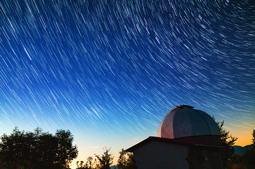 Observatory at night with star trails in the background. Long exposure with star trails.