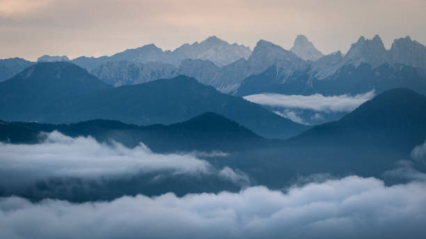 Evening in Italian Dolomites. Multiple layers of distant peaks fade into the background, and cloud inversion is forming at the bottom of the image. stock photo