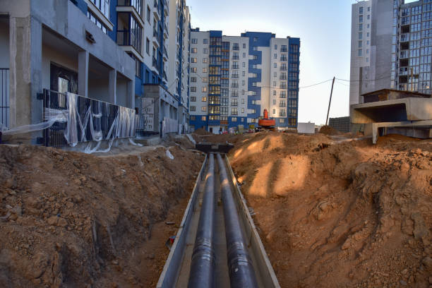 istock Laying heating pipes in a trench at construction site. Install underground storm systems of water main and sanitary sewer 1262908979
