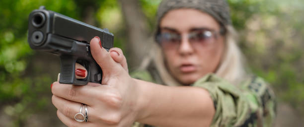 istock Attractive woman gun point aim to attacker. Close-up front view 1262909740