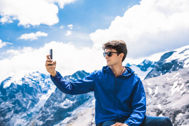 istock Young man using smart phone with view of Stelvio Pass in Italy 1262911161