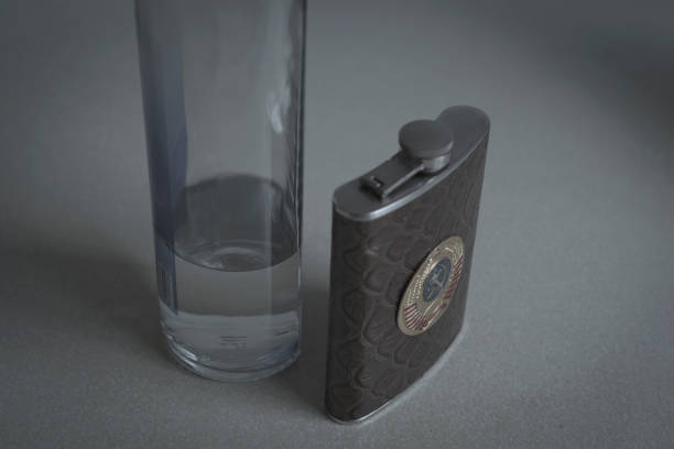 питьевая колба, кожа с гербом ссср и бутылка чистой жидкости (водка) - insulated drink container hip flask alcohol brown стоковые фото и изображения