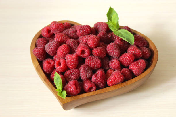 istock Close up of a ripe raspberry decorated with a mint leaf on a white background 1262911588