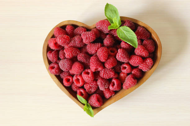 istock Sweet ripe raspberries are decorated with a mint leaf on a white background 1262911631