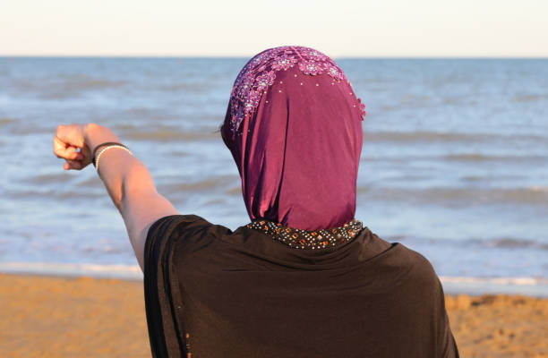 istock woman with veil on her head by the sea while pointing 1262912164