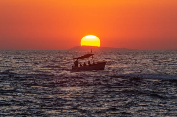 観光客はバックグロイドでイスキア島とプロチダ諸島と日没時に観光客のボートで日没時にボート - ischia island campania nautical vessel harbor ストックフォトと画像