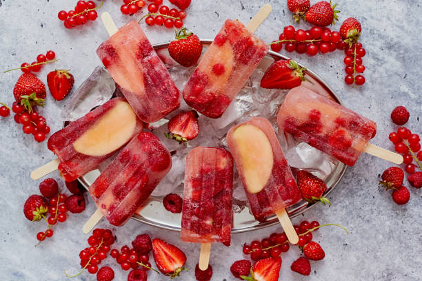istock Homemade raspberry, strawberry, apple and currant popsicles on metal plate with ice assorted berries 1262919402