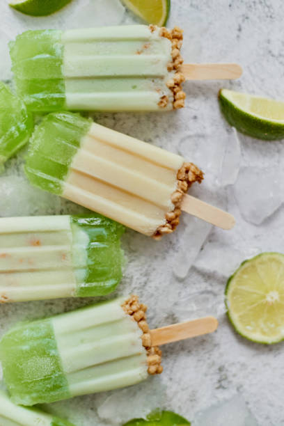 istock Lime and cream homemade popsicles or ice creams placed with ice cubes on gray stone backdrop 1262919427