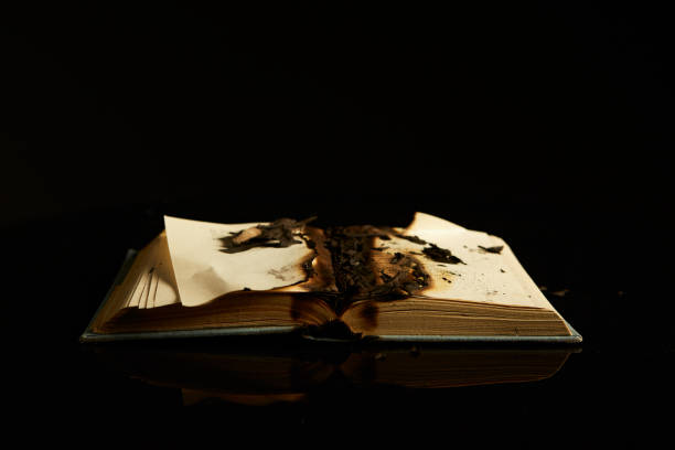 istock Burning book isolated on black background and reflective surface. Concept photography about literature, art, anti-utopia 1262919633