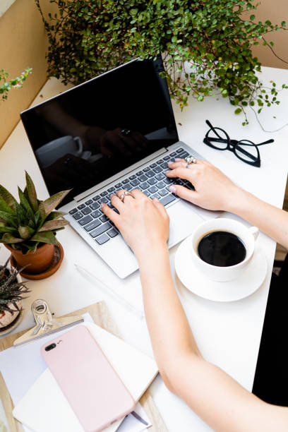 istock Woman's hands making notes in notepad in cozy summer office with laptop and green home plants 1262942224