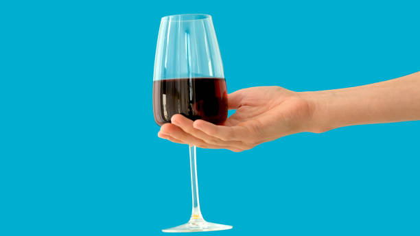 Crop person with glass of wine Anonymous person carrying glass goblet of fine red wine against bright blue background crystal chalice stock pictures, royalty-free photos & images
