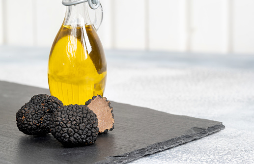 Delicacy mushroom black truffle with olive oil bottle on a light background .